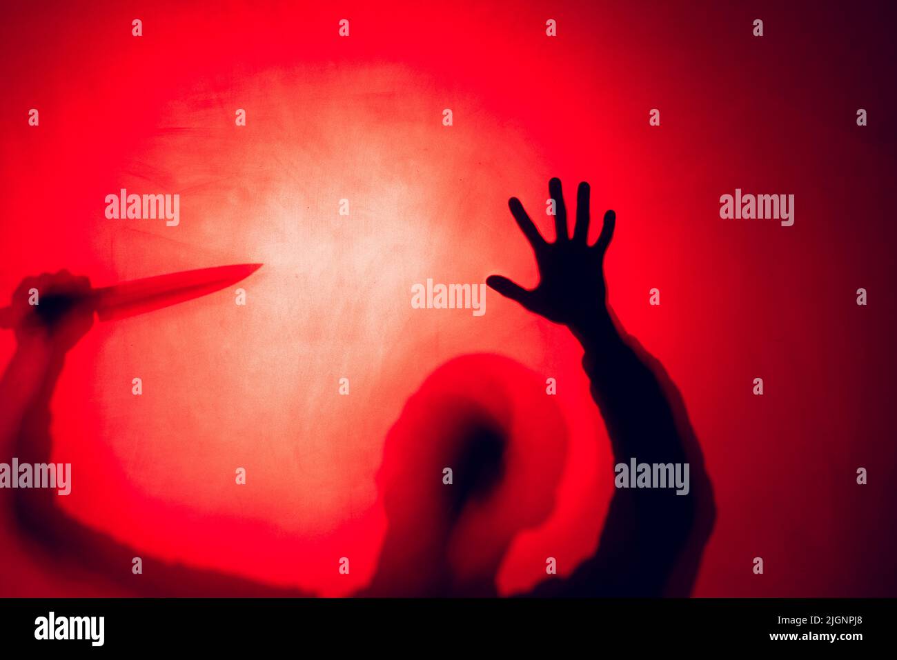Composition of silhouette of man holding knife on red background Stock Photo