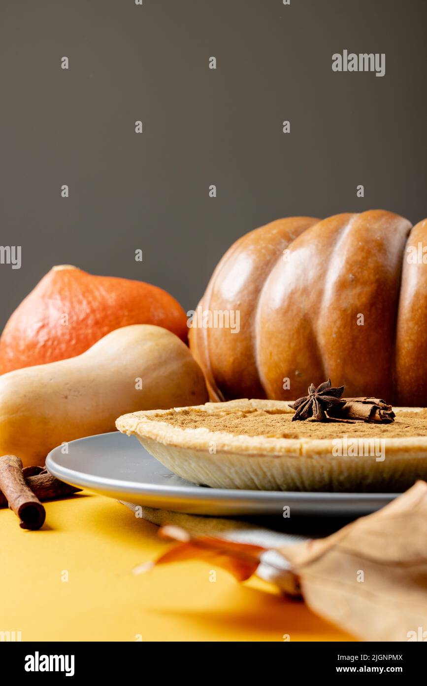 Composition of autumn leaves, pumpkins, spices and pie on grey ...