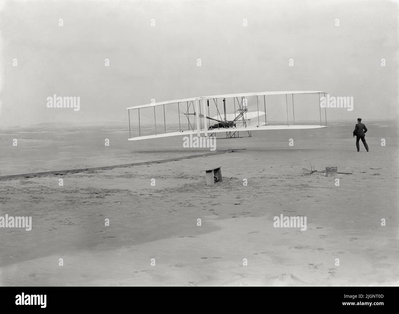 Vintage photo dated December 17th 1903 of the Wright Flyer on its first powered and controlled flight by Orville Wright with his brother Wilbur Wright at the side of the machine.  The first flight took place at Kitty Hawk, North Carolina, USA Stock Photo