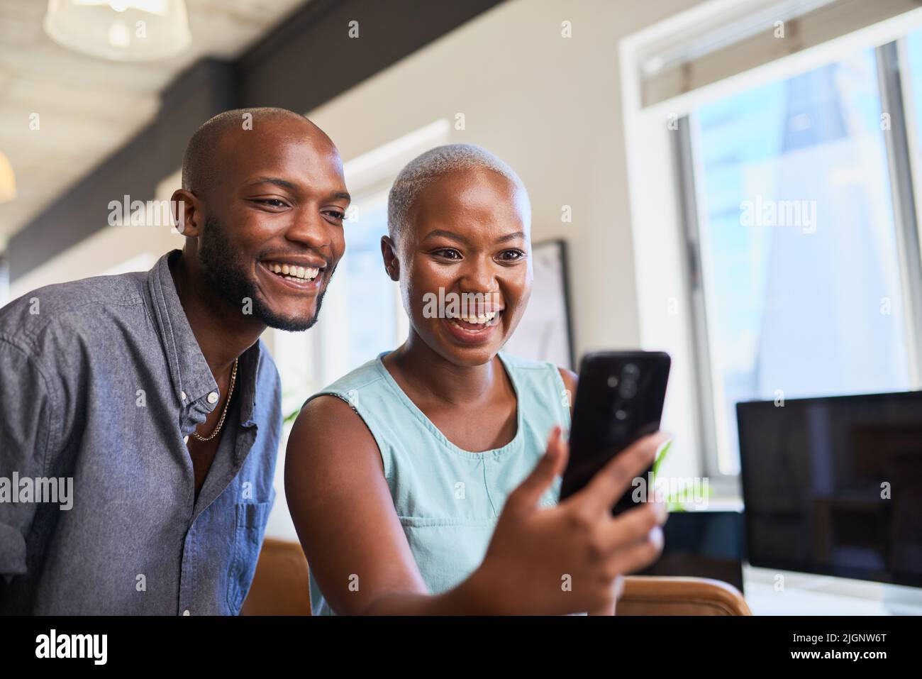 Two Black colleagues laugh on a video call on mobile phone Stock Photo