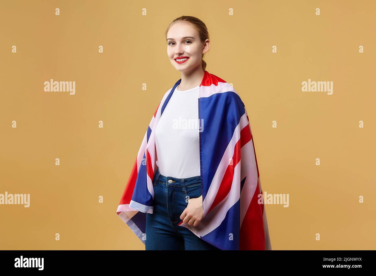 attractive blonde poses with a British flag. photo shoot in the studio on a yellow background. Stock Photo