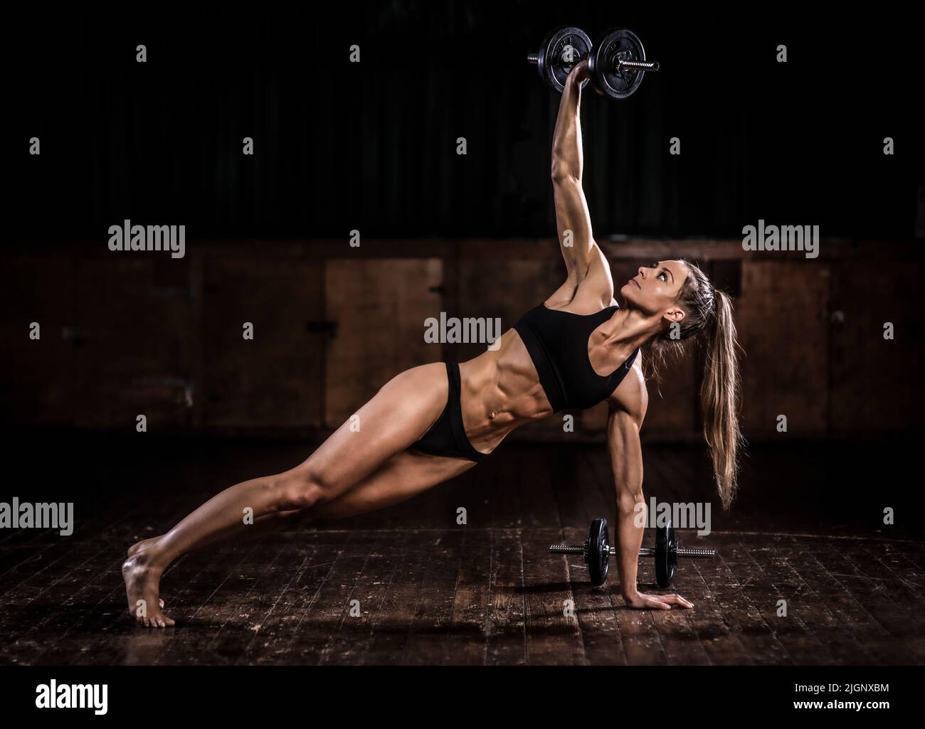 Female fitness model with toned body working out with weights, UK Stock Photo