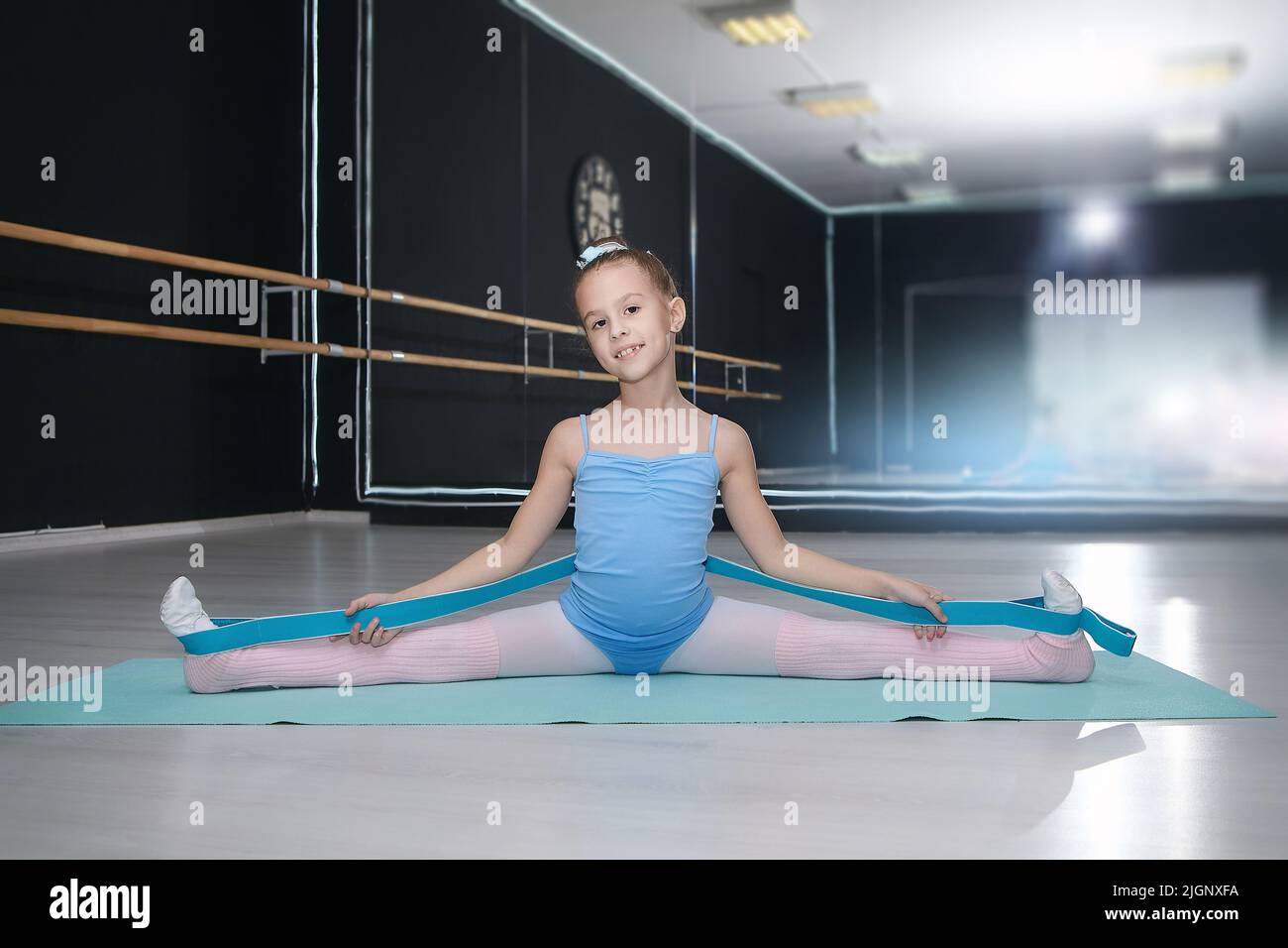 little girl does a stretch with an expander in a choreography school