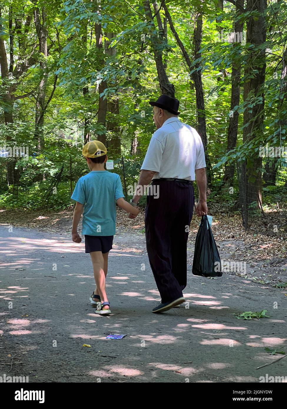 Grandpa and young grandson walk hand in hand on a walkway in Prospect Park, Brooklyn, New York. Stock Photo
