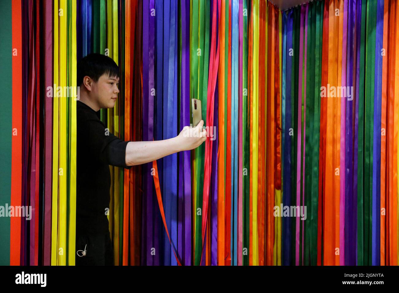 A transgender man takes a selfie inside a booth with rainbow colors at a shopping mall in Bangkok.  Lawmakers in Thailand gave initial approval to legalizing same-sex unions, a step closer towards becoming the second territory in Asia to legalize same-gender marriages. Thailand. Stock Photo