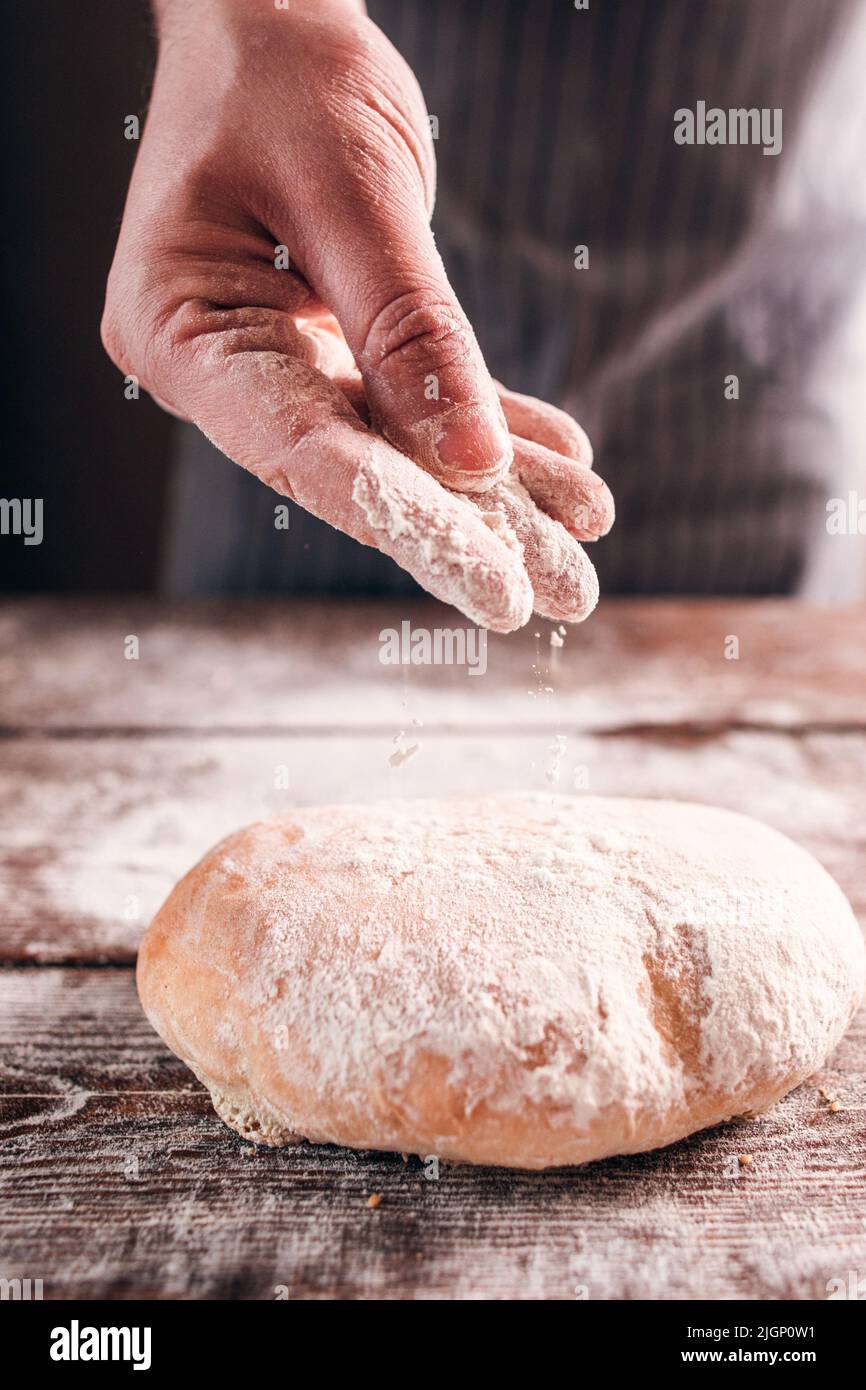 Baker hand sprinkle flour on fresh bun closeup Stock Photo Alamy