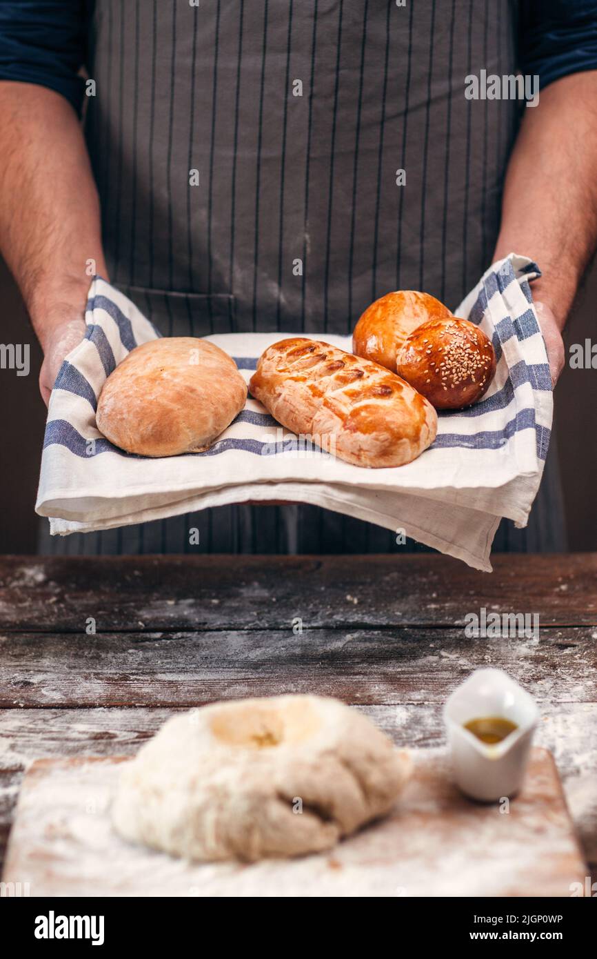 Man with warm crusty bread above dough free space Stock Photo