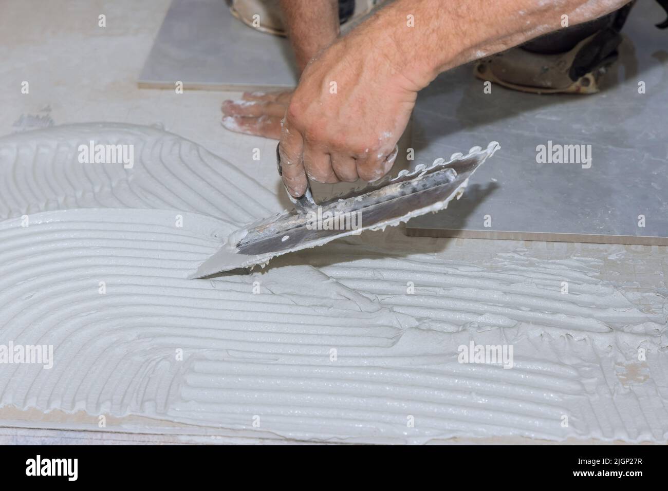 Putting adhesive on the bathroom floor by spreading wet mortar before