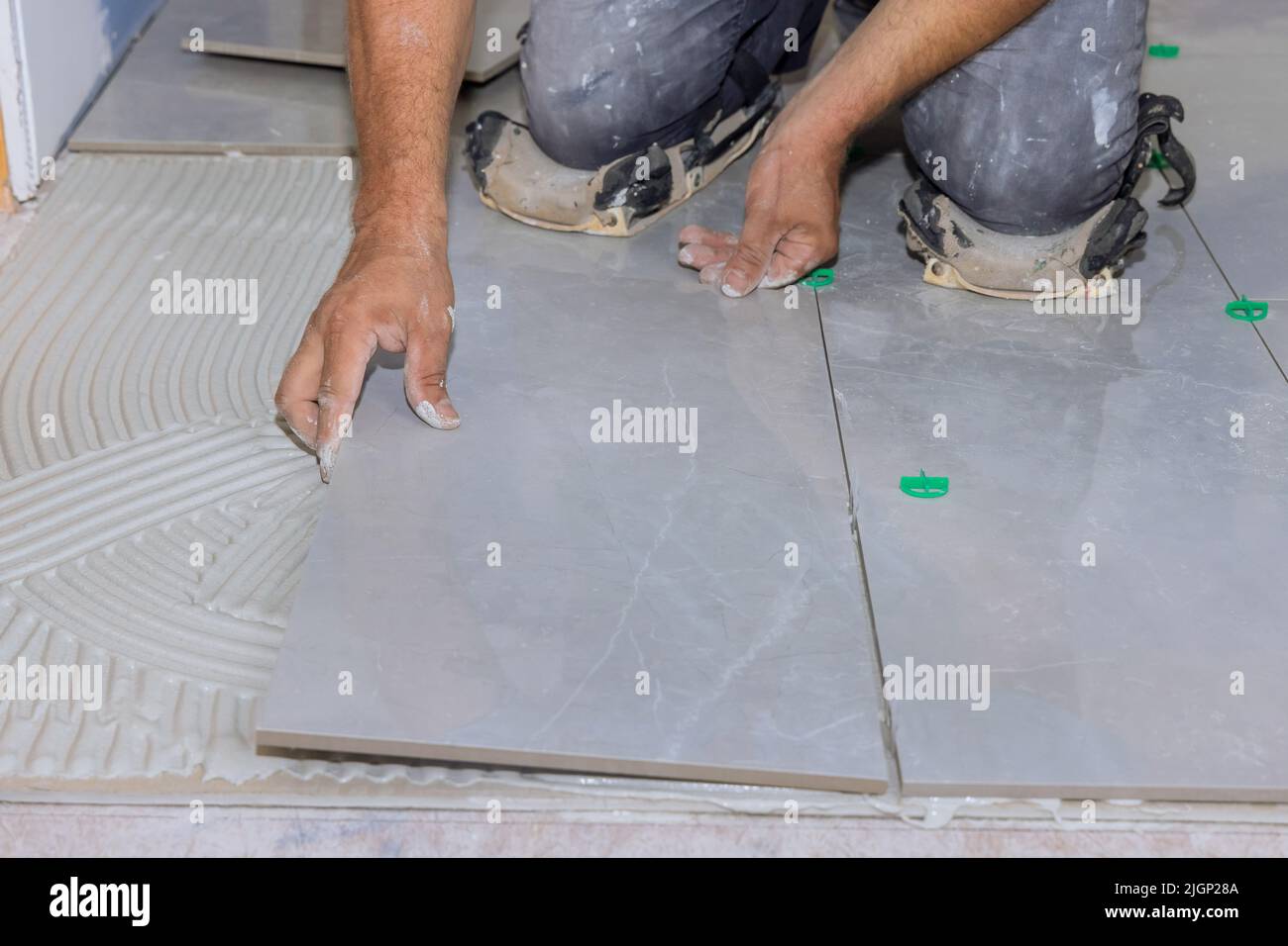 Installing ceramic tiles on an adhesive surface while working on the construction Stock Photo
