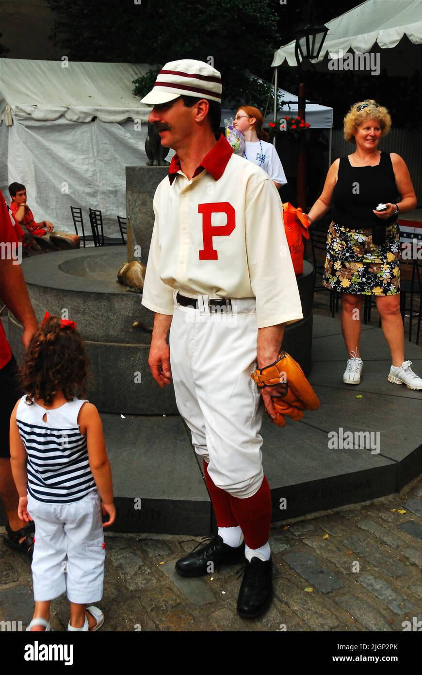 An adult man dresses in a Old Time Baseball uniform costume teaching children of the sport during the turn of the 20th Century in Philadelphia Stock Photo