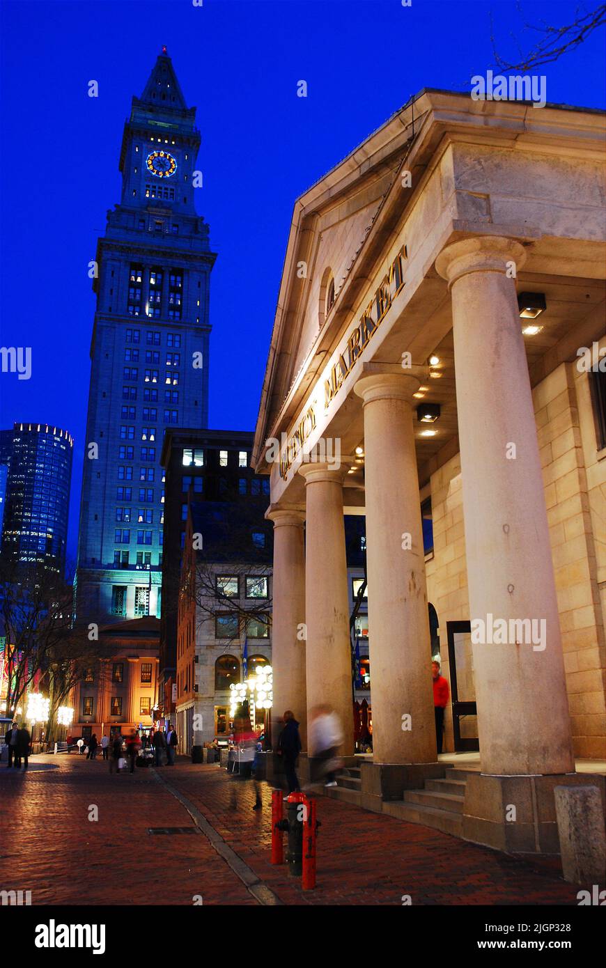 The lights of the historic Quincy Market and Custom House in Boston are illuminated and reflected in the city streets on a rainy winter day at dusk Stock Photo