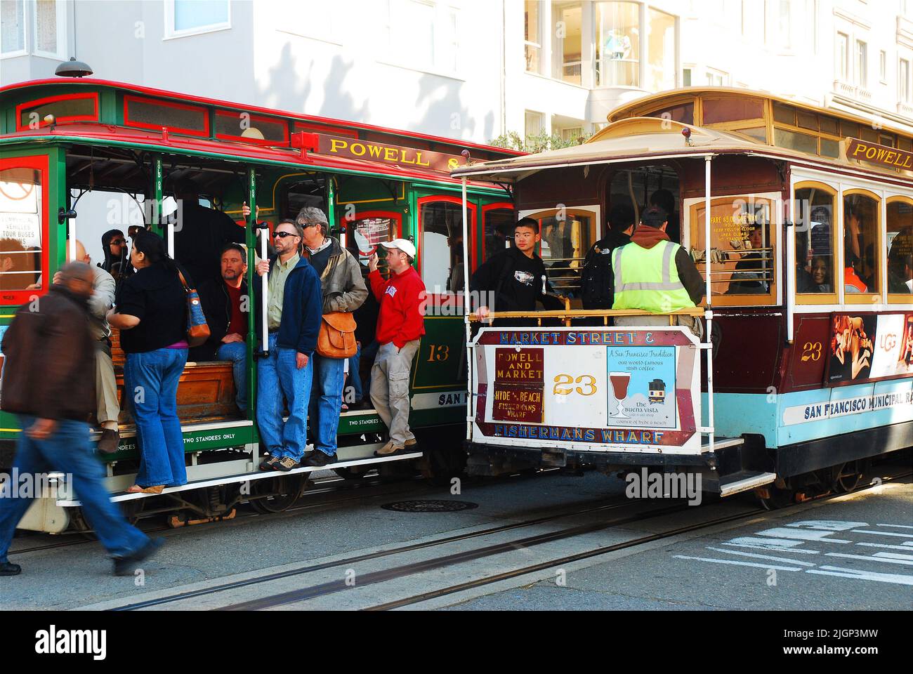 People begin to board a cable car in San Francisco just as another pulls away on the street Stock Photo