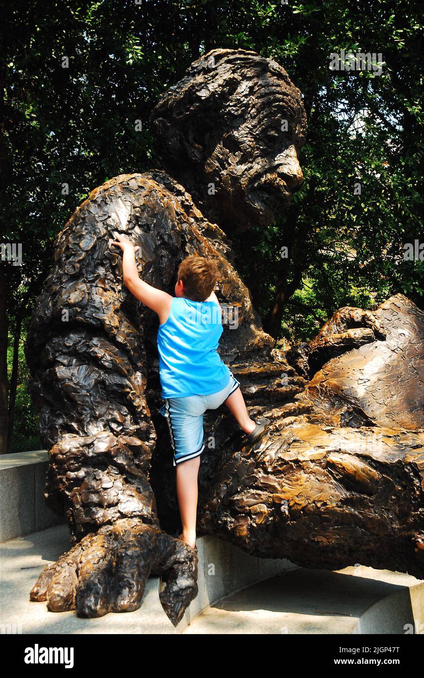 A young boy climbs a sculpture of famous scientist Albert Einstein outside of the National Academy of Sciences in Washington, DC Stock Photo