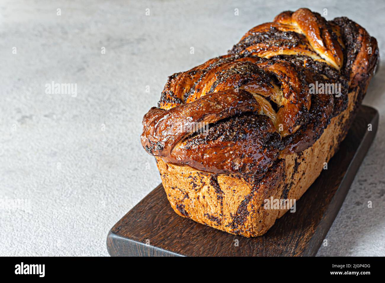 Freshly baked brioche/Babka with poppy seeds and chocolate on a wooden board. Braided dessert bread. Homemade baking, national pastries. Estonian krin Stock Photo