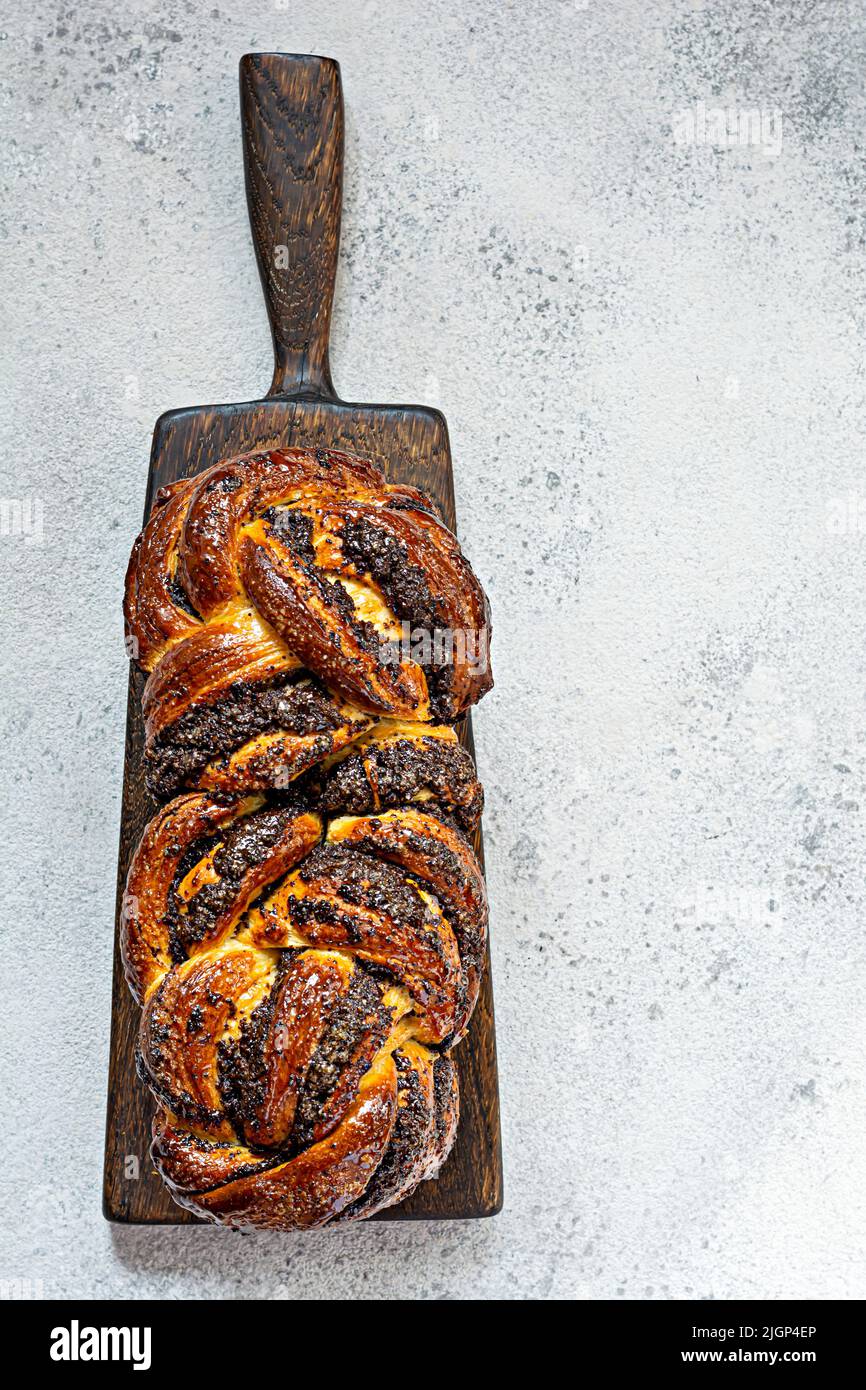 Freshly baked brioche/Babka with poppy seeds and chocolate on a wooden board. Braided dessert bread. Homemade baking, national pastries. Estonian krin Stock Photo