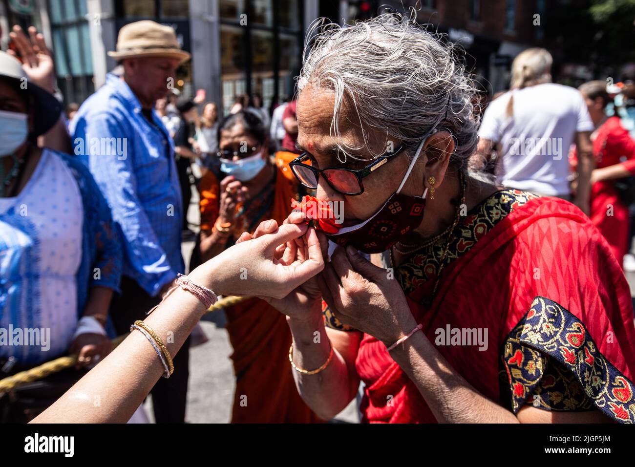 A devotee smells on a rose thrown from the main cart during the celebration. Stock Photo