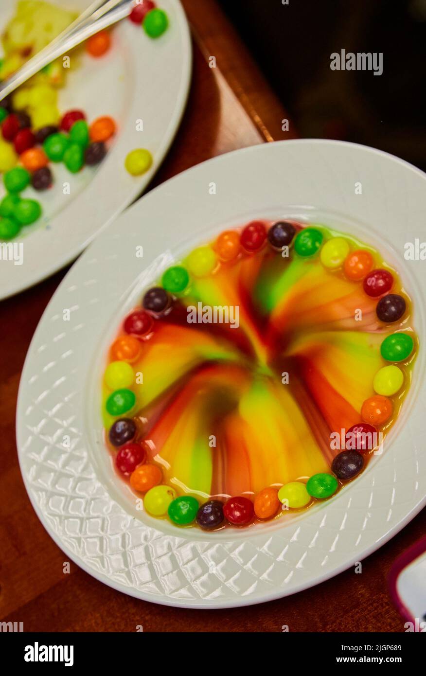 Skittles Rainbow made with water in plate at kids party.  Colors melt and merge into rainbow pattern. Stock Photo