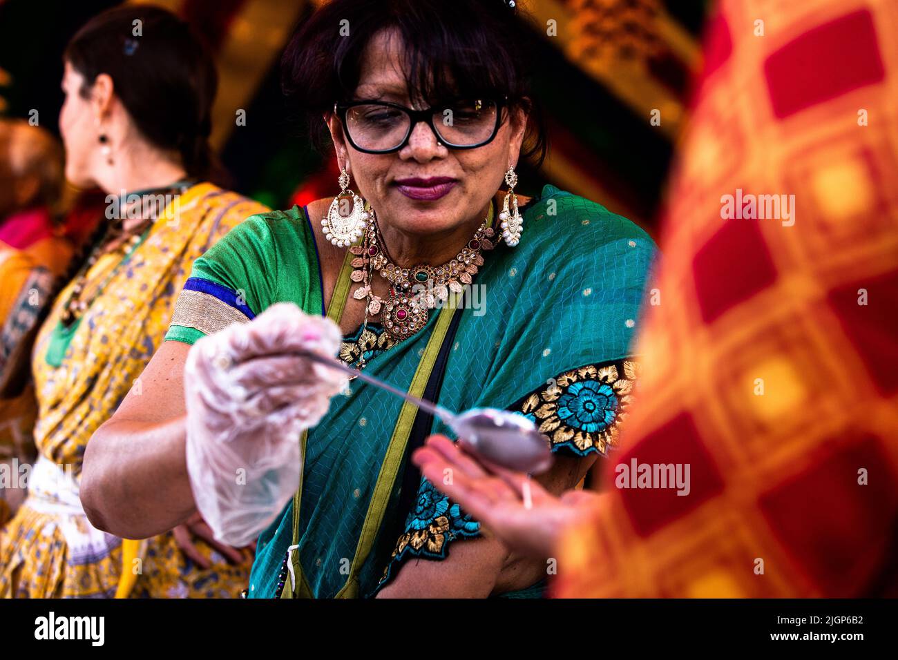 A volunteer serves food to devotees during the celebration. Stock Photo