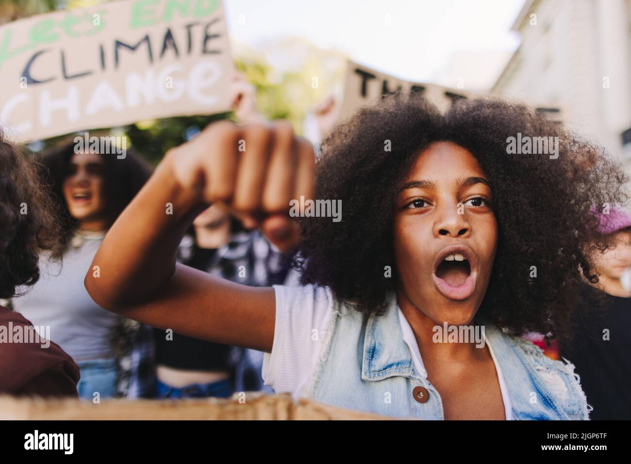 Multiethnic teenagers taking action against climate change. Group of climate activists shouting slogans while marching in the streets. Diverse young p Stock Photo