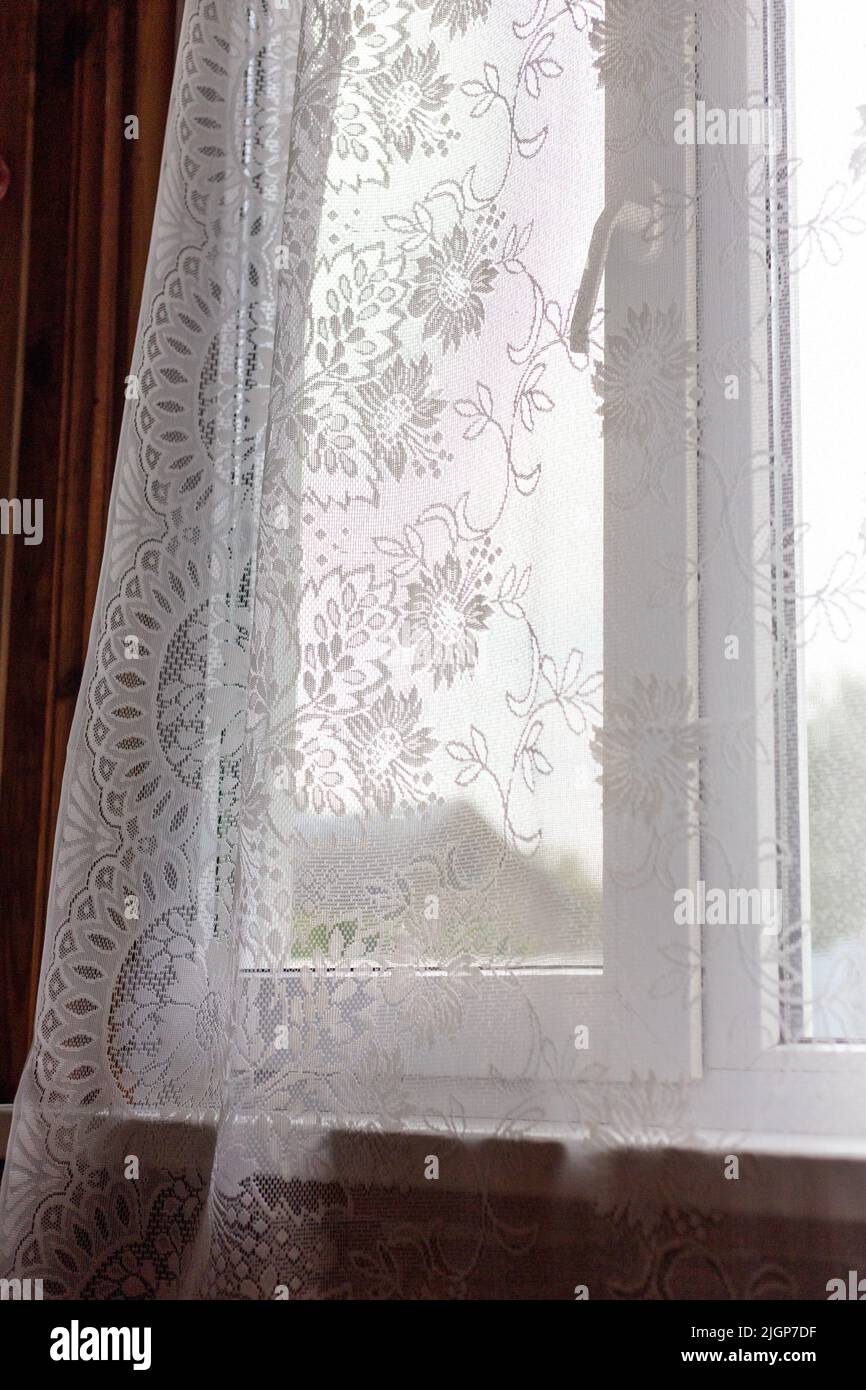 Window with openwork curtains. Transparent curtains with patterns. Stock Photo