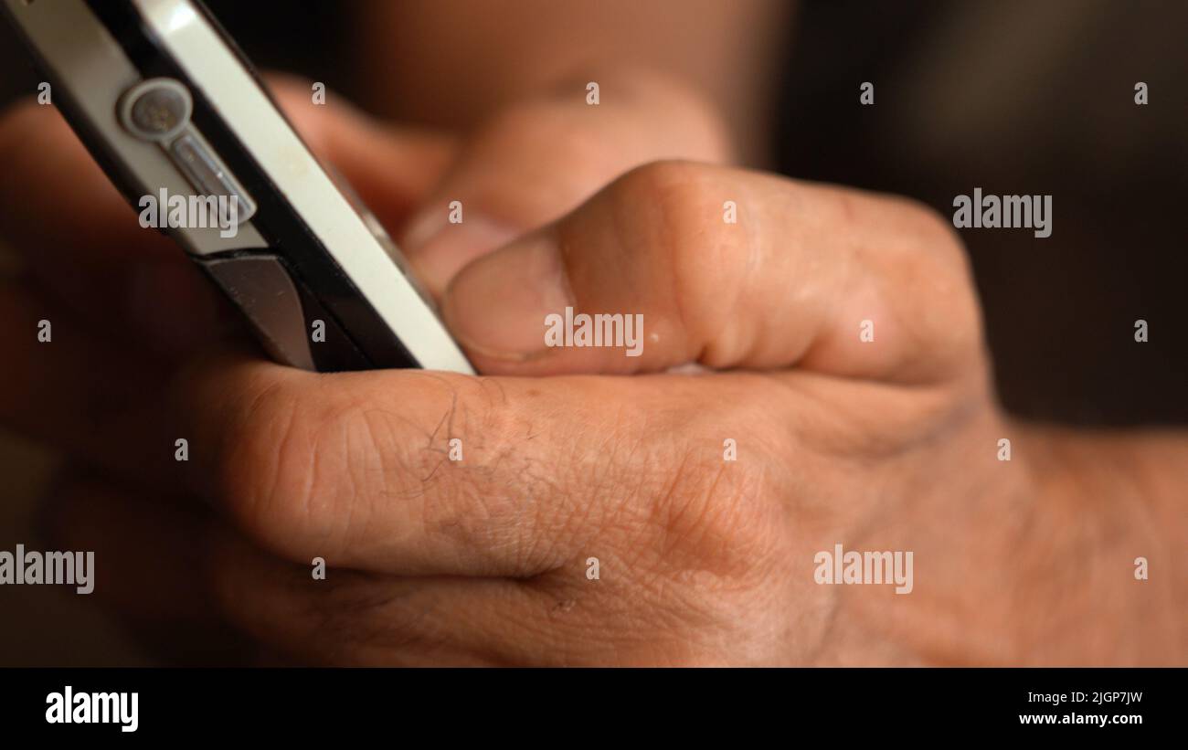 A button phone in the wrinkled hands of an elderly person Stock Photo