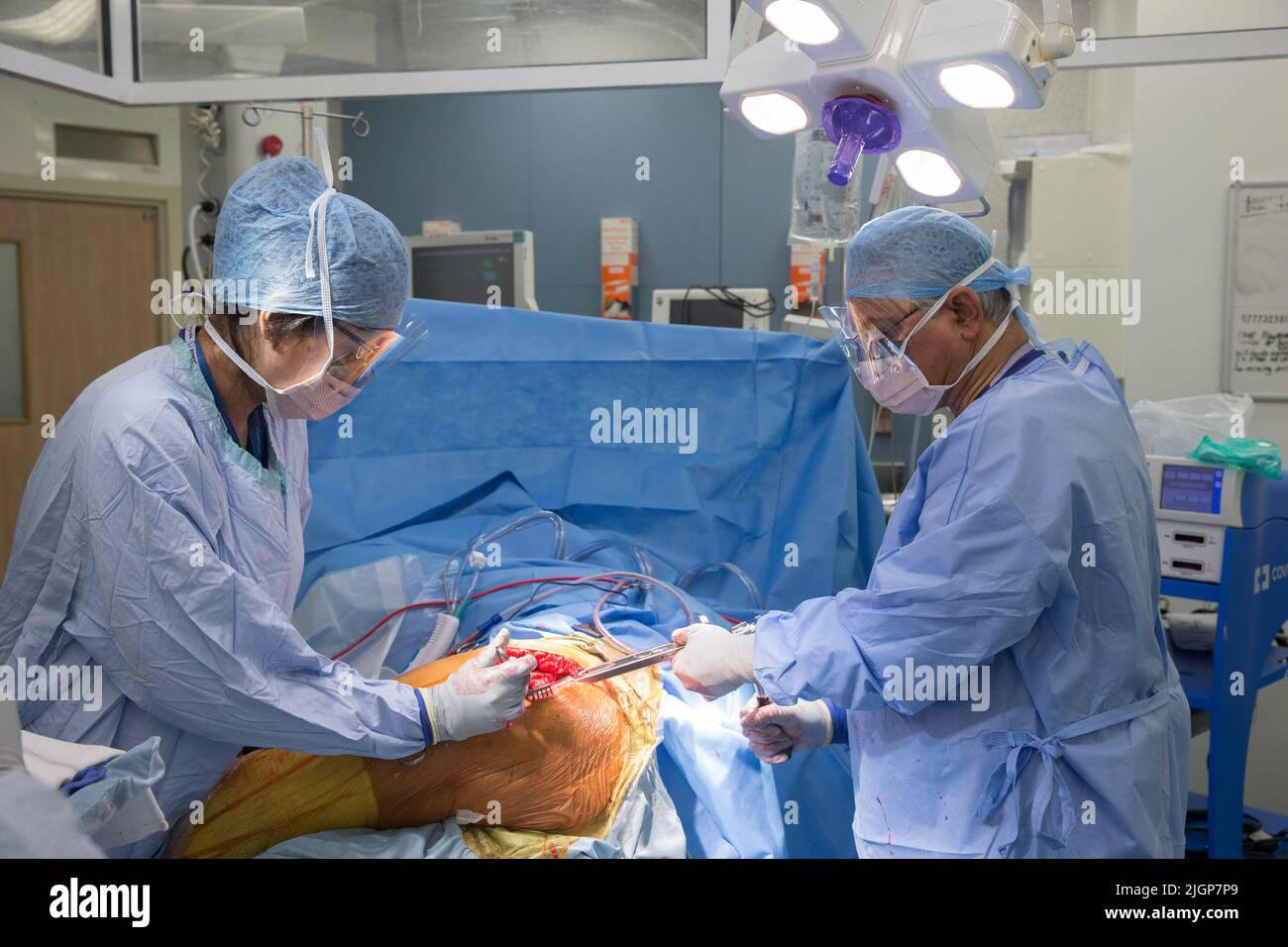 A surgeon and NHS staff perform knee surgery, also known as