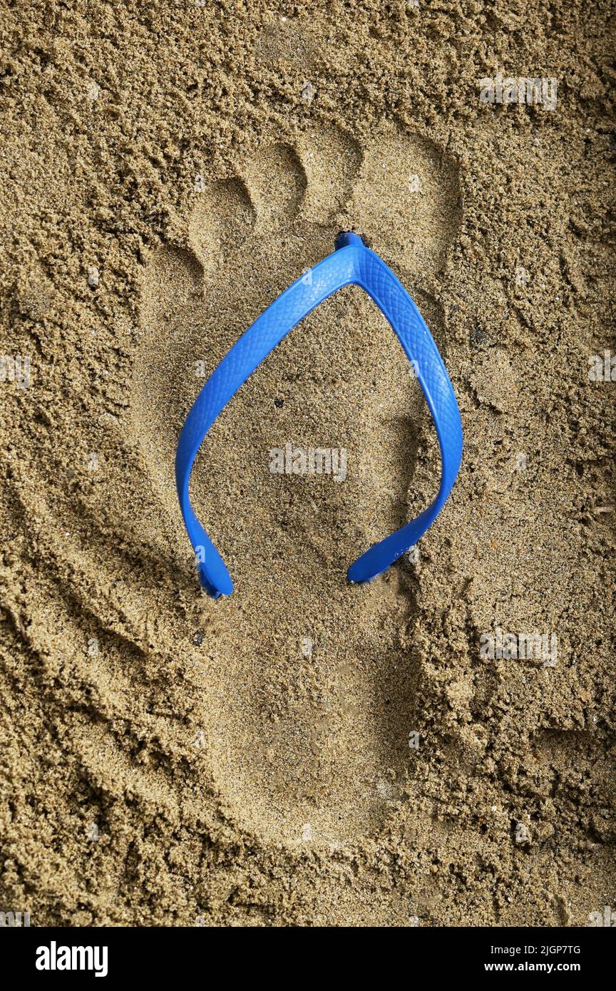 Abstract Footprint Blue Rubber Beach Flip Flops on Sand Stock Photo