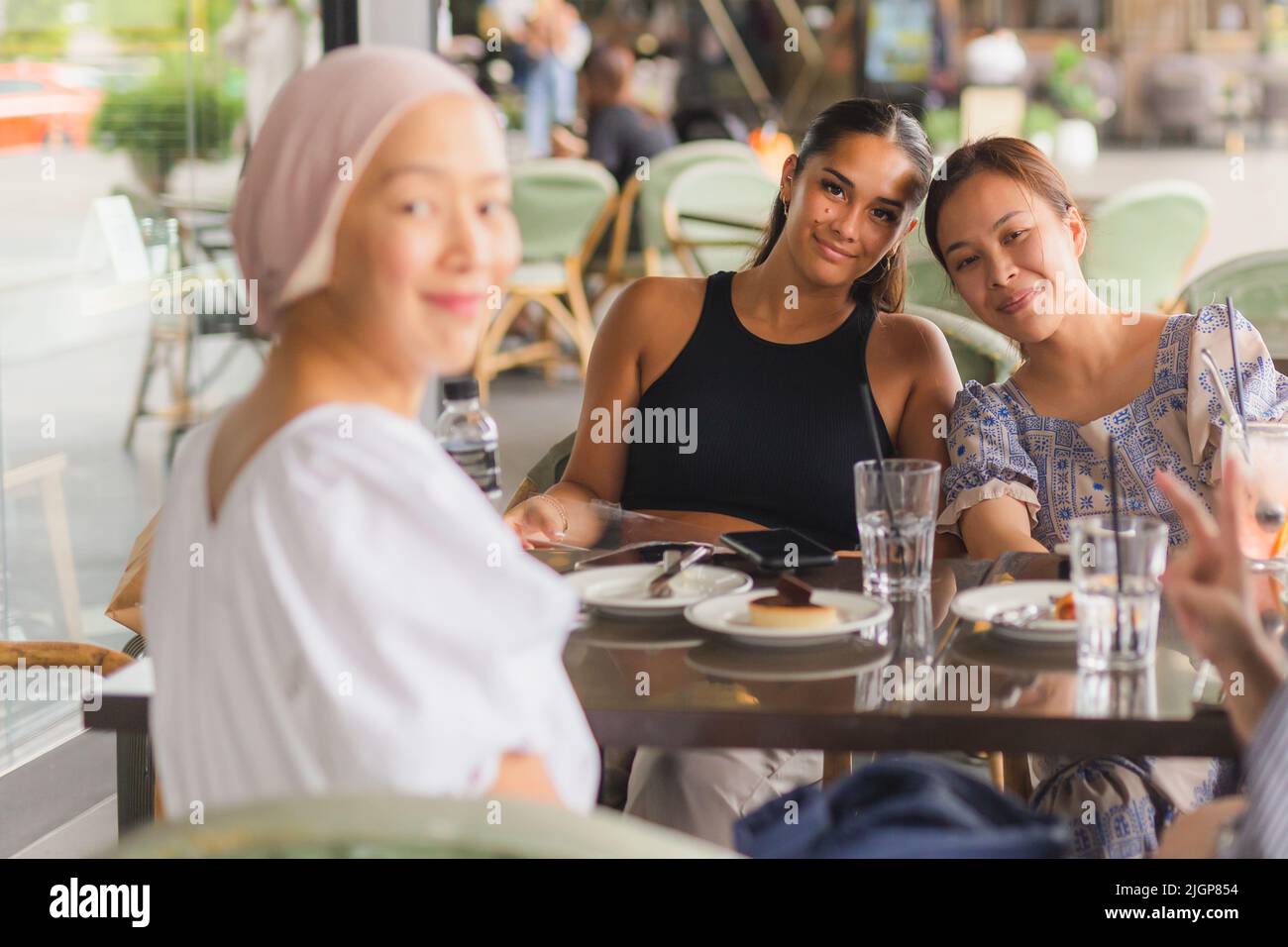 Happy lady having coffee and cake together at cafe outdoors. Stock Photo