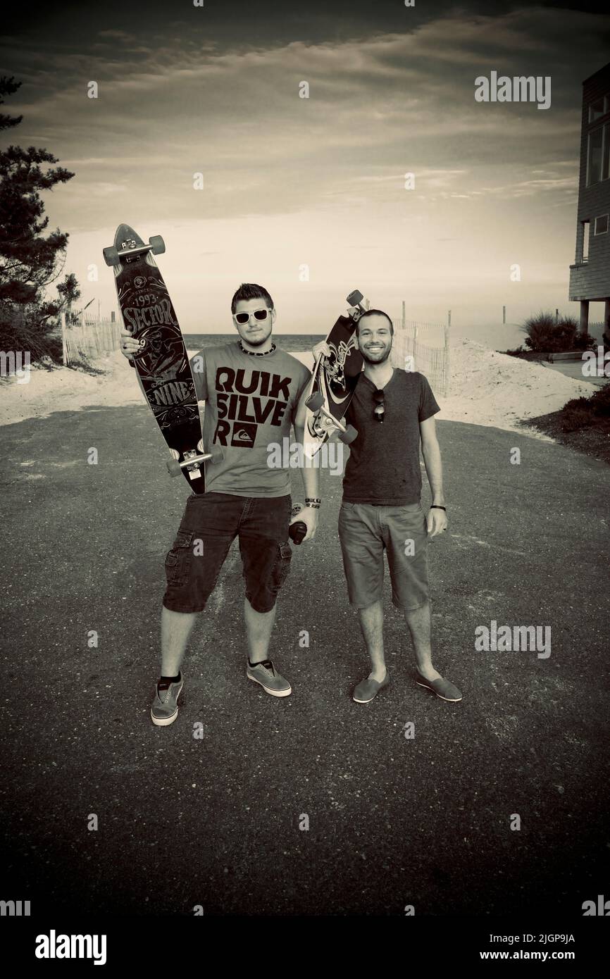 Two 20 something dudes with their long board skate boards on a street at the Jersey shore. Stock Photo