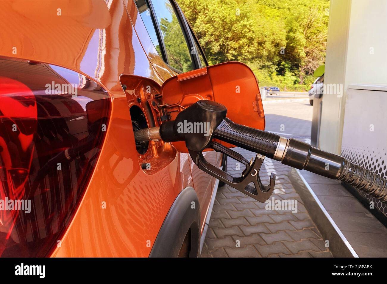 Fill car with fuel in petrol station. Pumping gasoline fuel in orange car at a gas station. Close up. Stock Photo