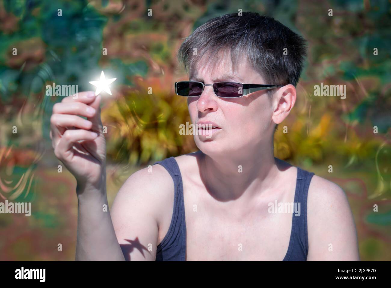 Woman sitting outdoor and holding shining star in her hands. Stock Photo