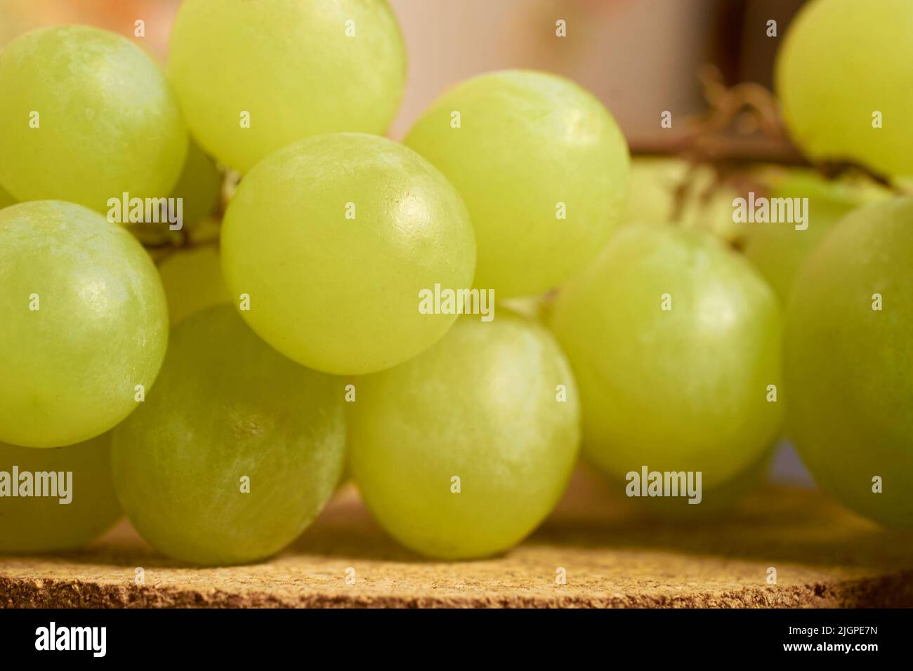 A bunch of green grapes lies on a cork stand. Close-up. Selective focusing Stock Photo