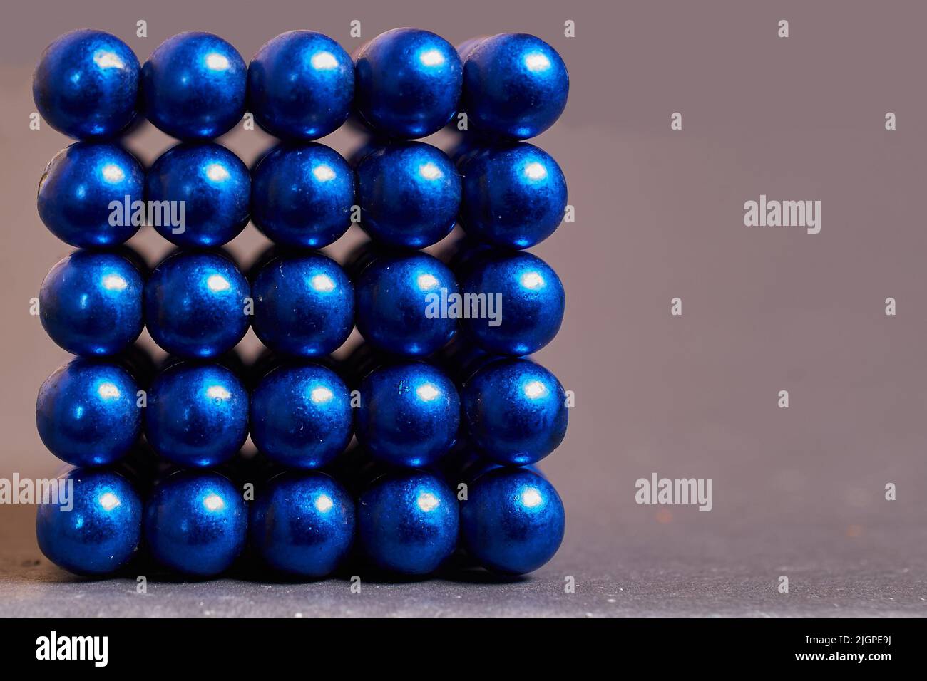 Magnetic cube made of blue metal balls on a colored background Stock Photo