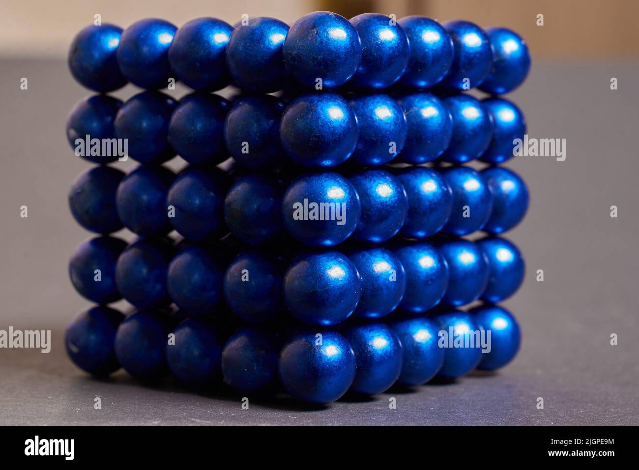 Magnetic cube made of blue metal balls on a colored background Stock Photo