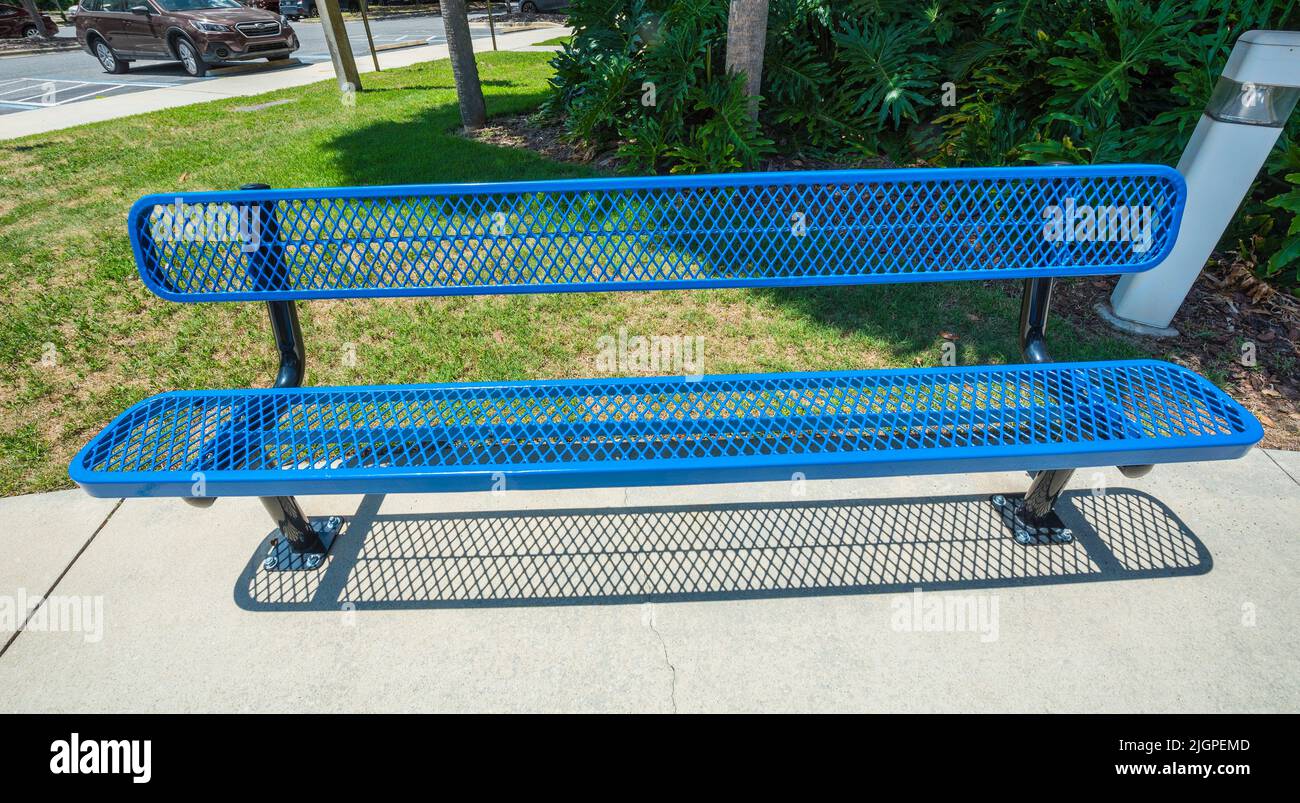 Bright blue metal bench sits outside an office building in Gainesville, Florida. Stock Photo