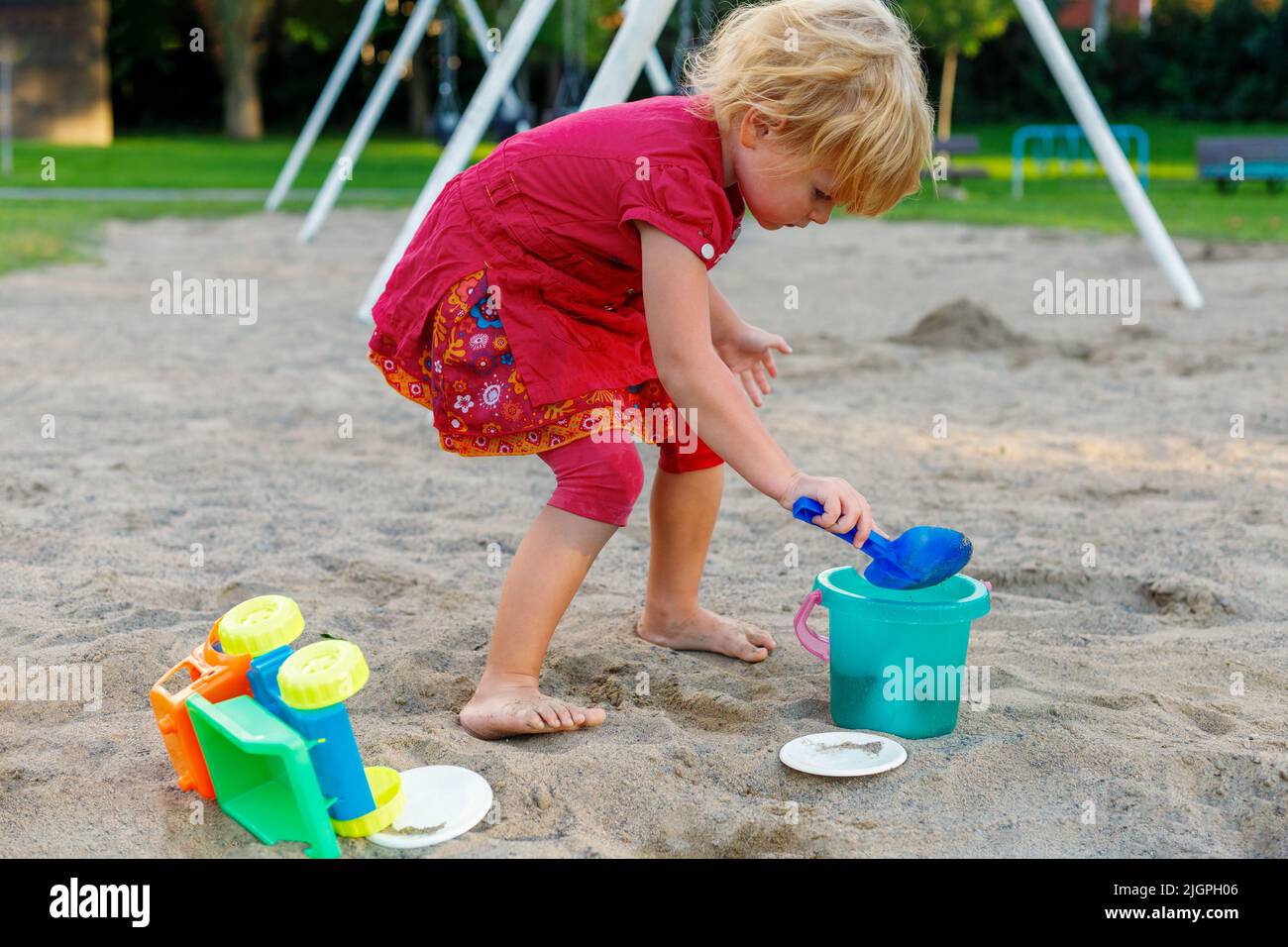 Small child playing with sand and toys in park. Small kid at playground in summer Stock Photo