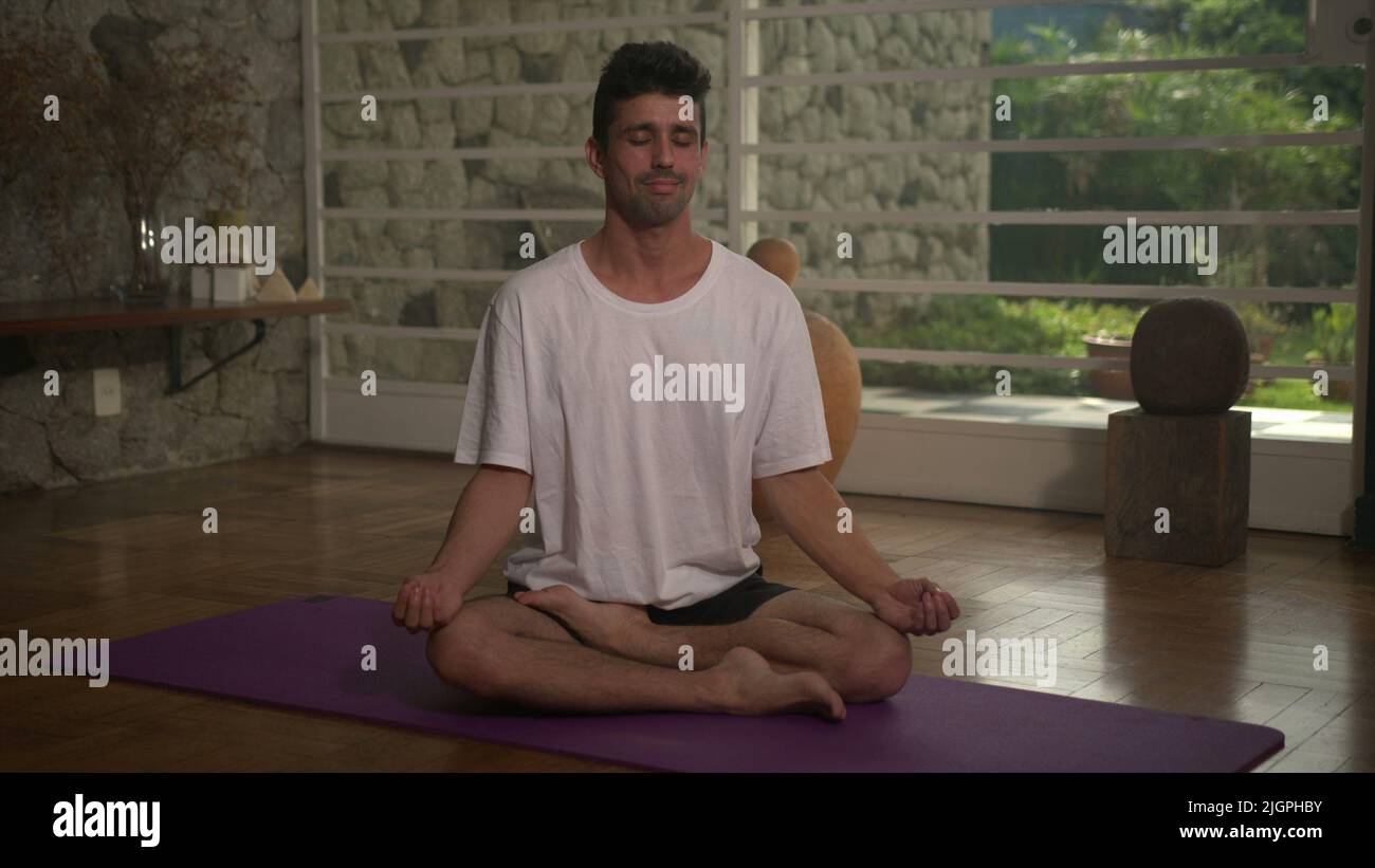 One mindful person practicing meditation sitting at home on his Yoga