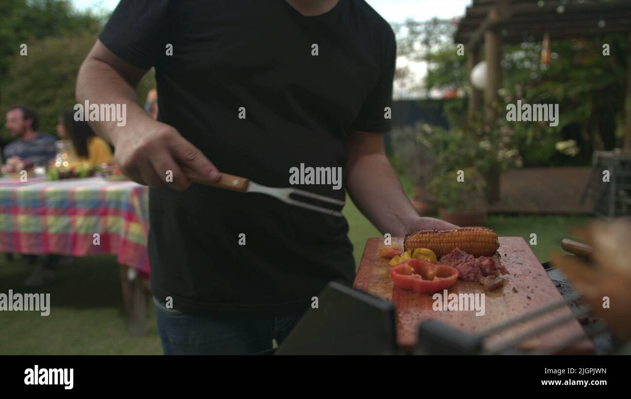 Barbecue chef bringing food to friends and family gathered around table