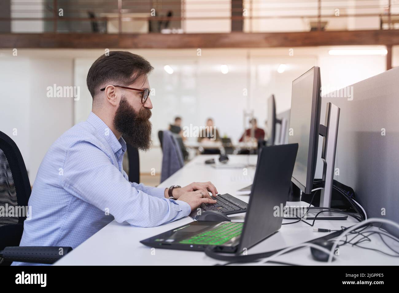 Senior computer programmer developer working in IT office, sitting at desk and coding, working on a project in software development company or startup Stock Photo