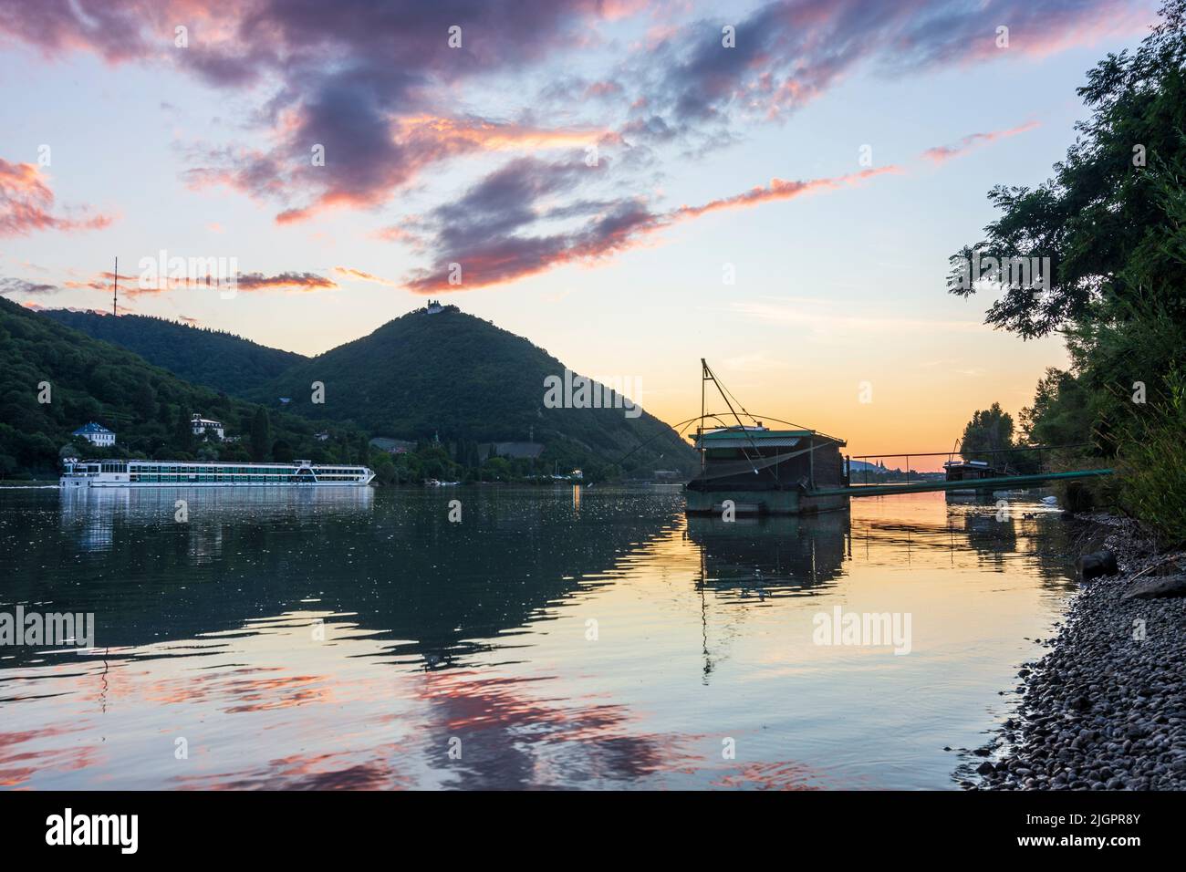 Wien, Vienna: sunset at river Donau (Danube), view to mountain Kahlenberg (left) and Leopoldsberg (with church), Daubel boat with lifting fishing net, Stock Photo