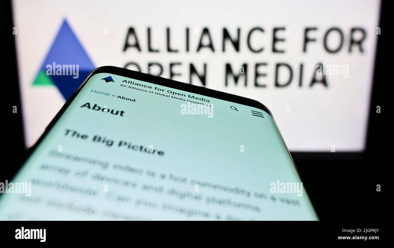 Smartphone with website of consortium Alliance for Open Media (AOMedia) on screen in front of business logo. Focus on top-left of phone display. Stock Photo