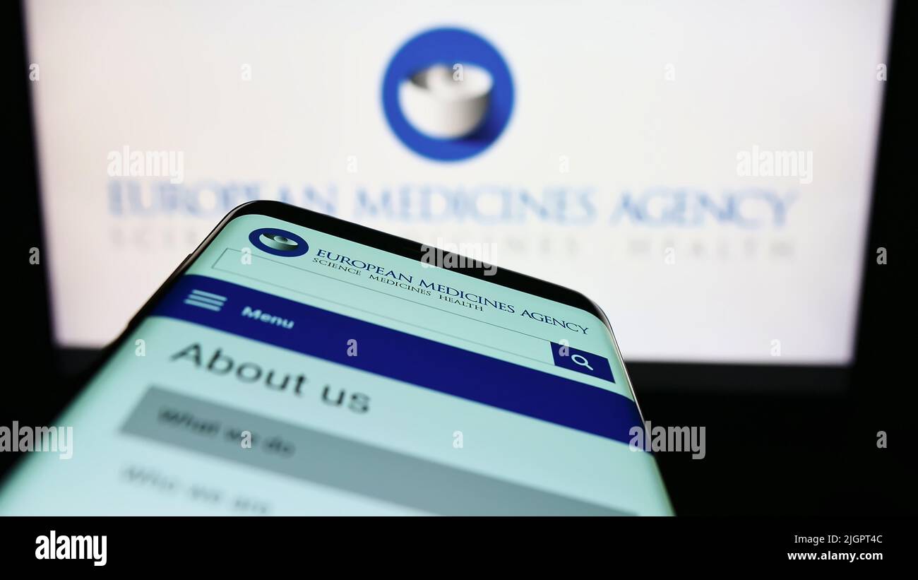 Mobile phone with webpage of EU agency European Medicines Agency (EMA) on screen in front of logo. Focus on top-left of phone display. Stock Photo