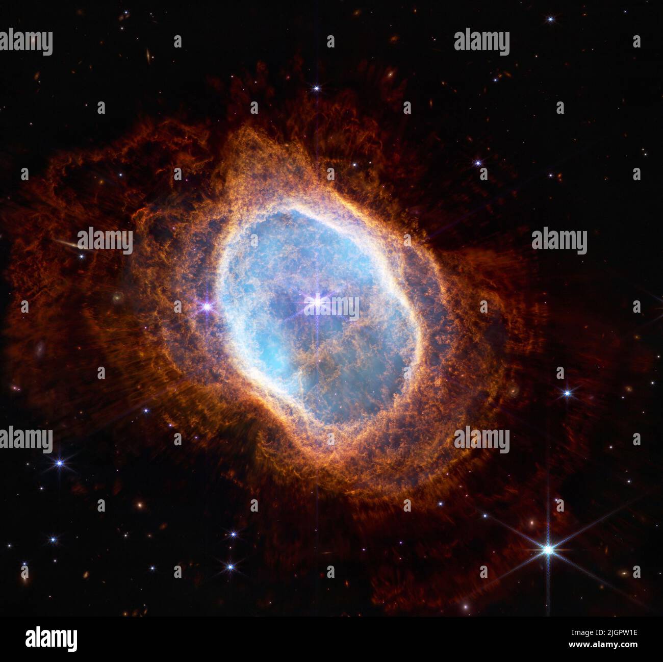 July 12, 2022: Observation of the Southern Ring Nebula in near-infrared light, at left from NASA's Webb Telescope. This scene was created by a white dwarf star, the remains of a star like our Sun after it shed its outer layers and stopped burning fuel though nuclear fusion. Those outer layers now form the ejected shells all along this view. In the Near-Infrared Camera (NIRCam) image, the white dwarf appears to the lower left of the bright, central star, partially hidden by a diffraction spike. This white dwarf star is cloaked in thick layers of dust. Over thousands of years and before it beca Stock Photo