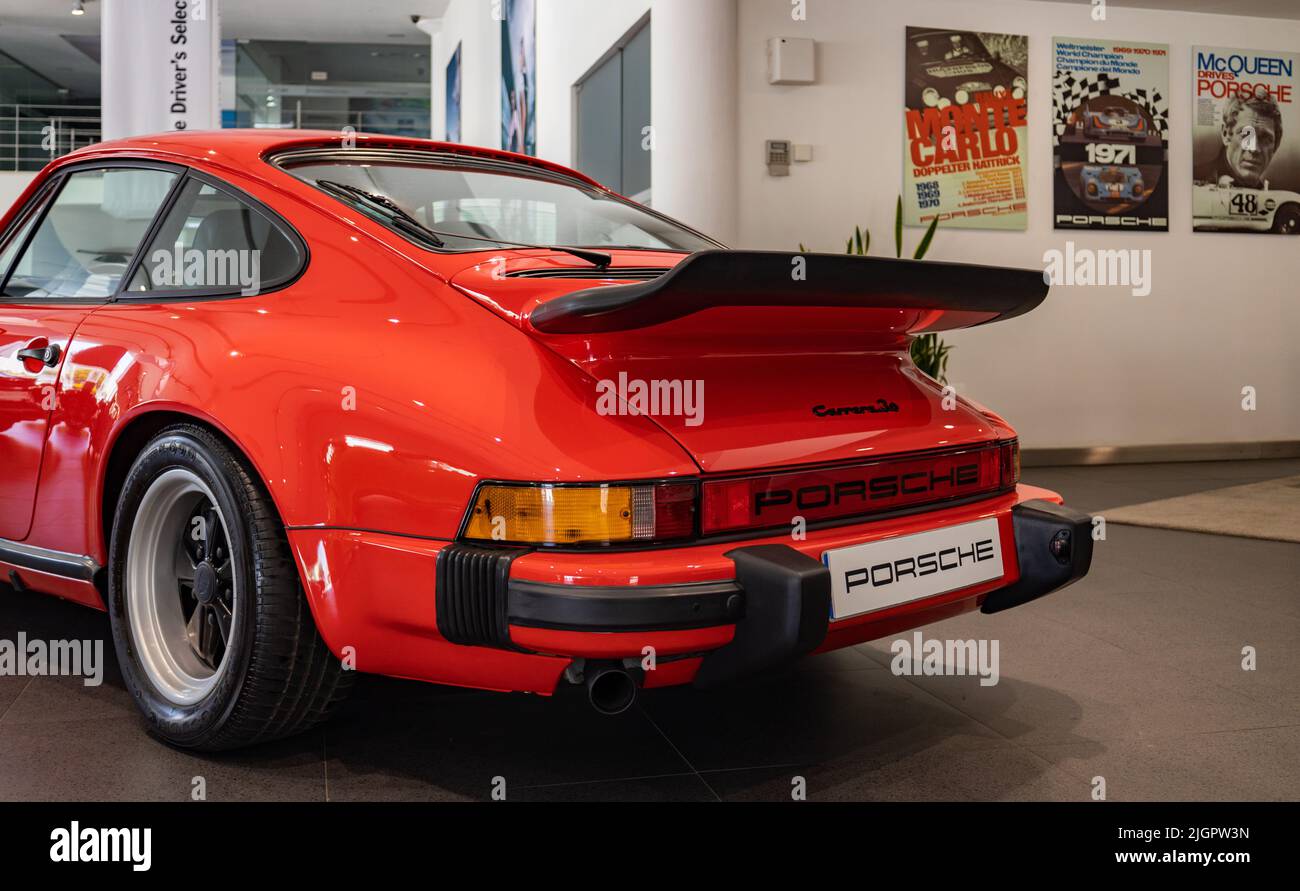 A picture of a red Porsche 911 Carrera 3.0 inside a dealership. Stock Photo