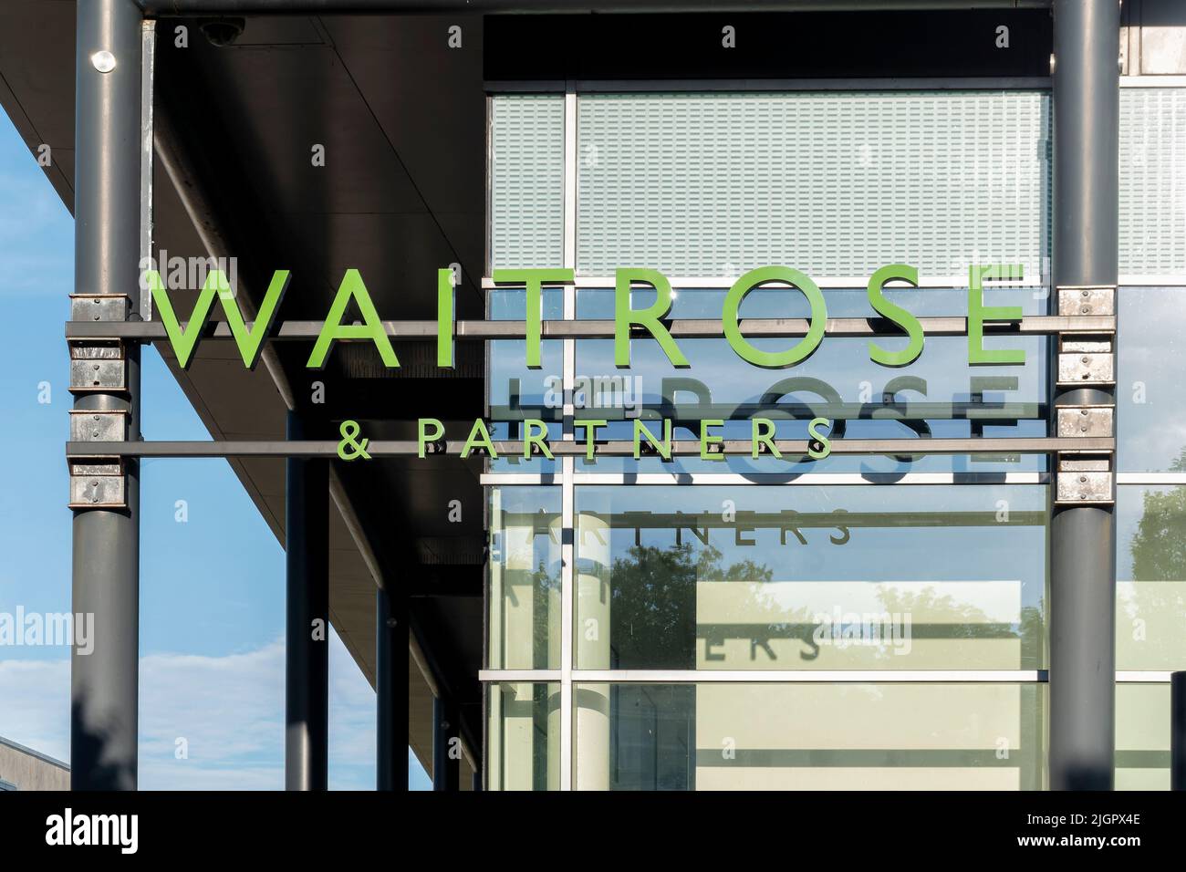 A Waitrose and partners shop sign displayed on the outside of one of their supermarkets. The sign is written in the shops branding and colours Stock Photo