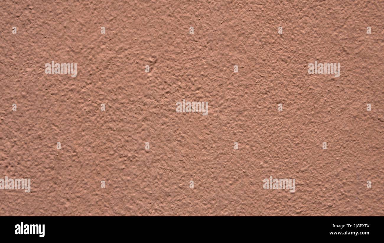 Delicate peach color textured concrete wall of the house. Beautiful abstract pink background for a construction project. Decorative plaster, surface finish. Stock Photo