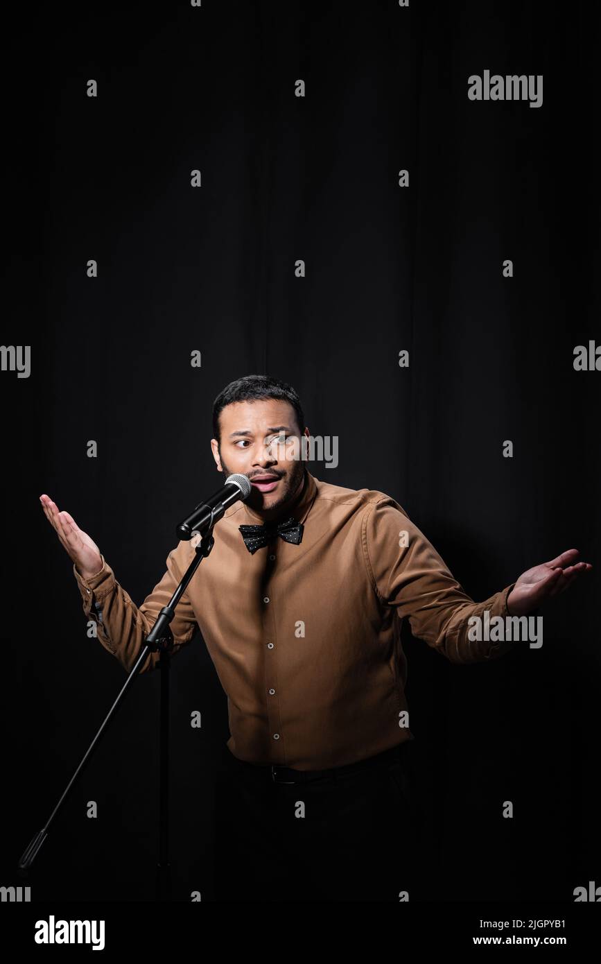 indian stand up comedian gesturing while telling jokes into microphone