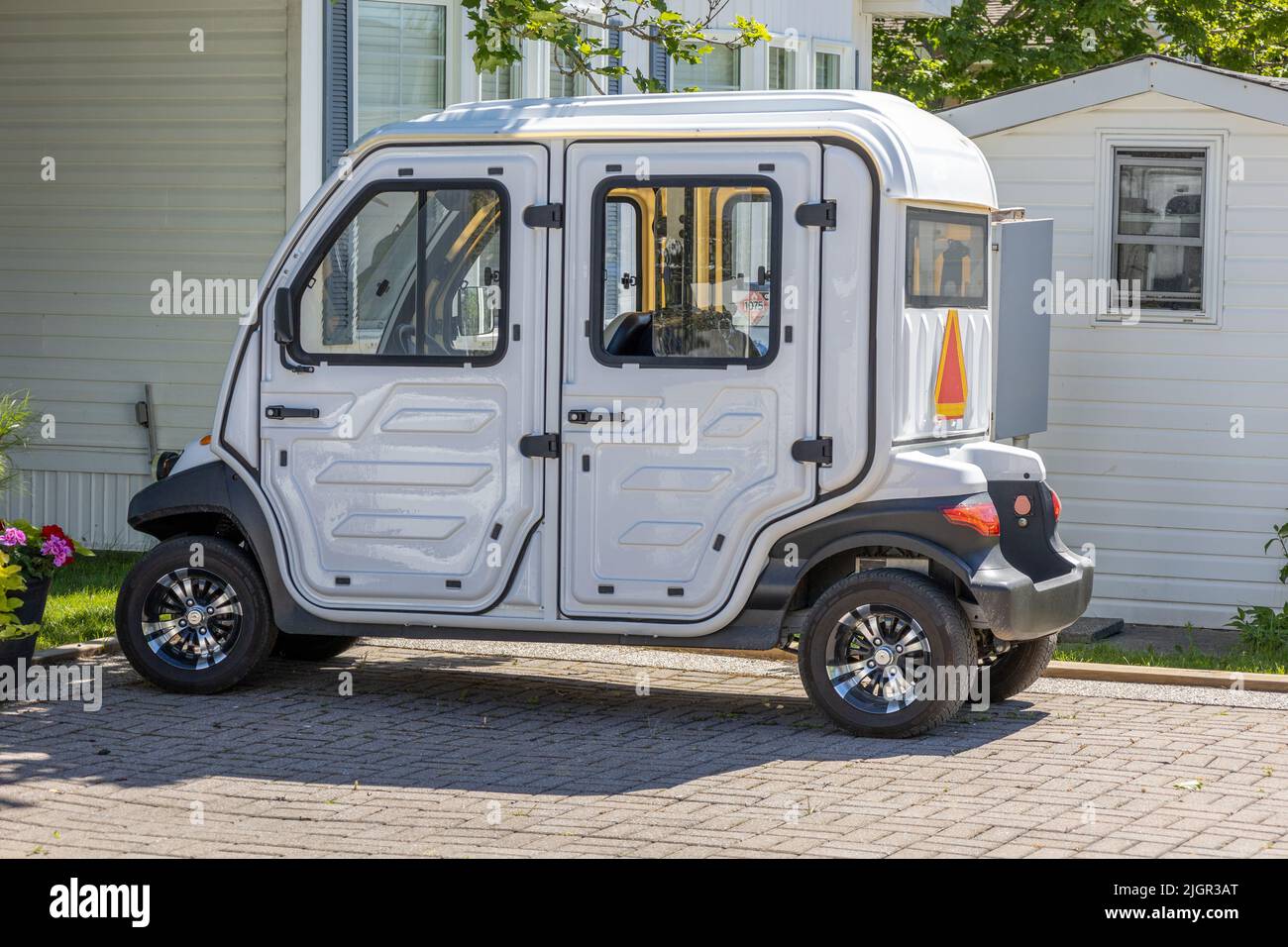 AGT Electric LSV 4 Fully Enclosed Electric Golf Cart Used As A Commercial Utility Vehicle, Small EV Used In A Gated Community Stock Photo