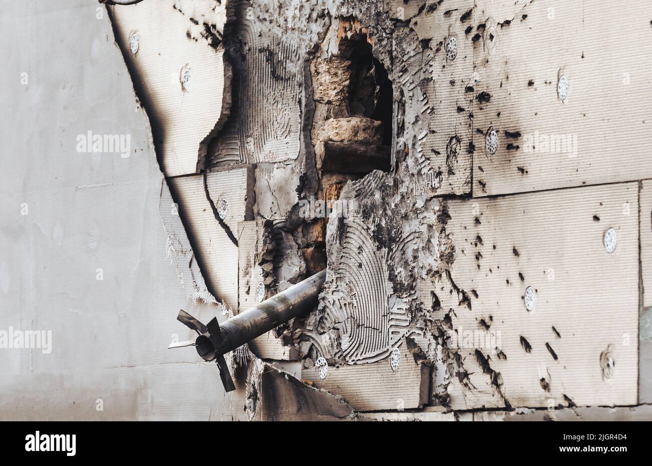 An unexploded rocket is seen in the wall of a house located in a ...