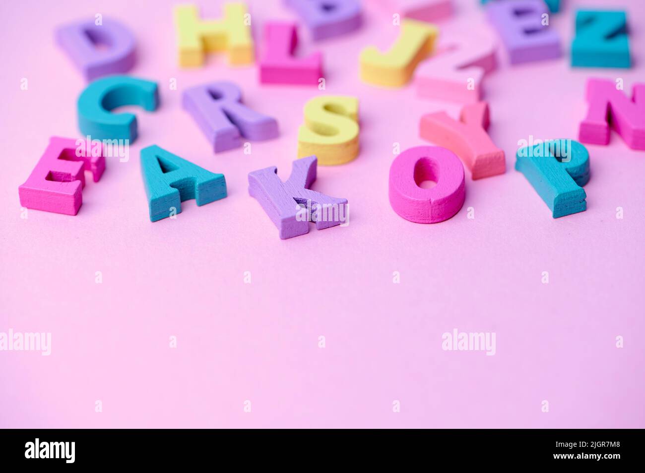 several colored wooden letters on pink background Stock Photo